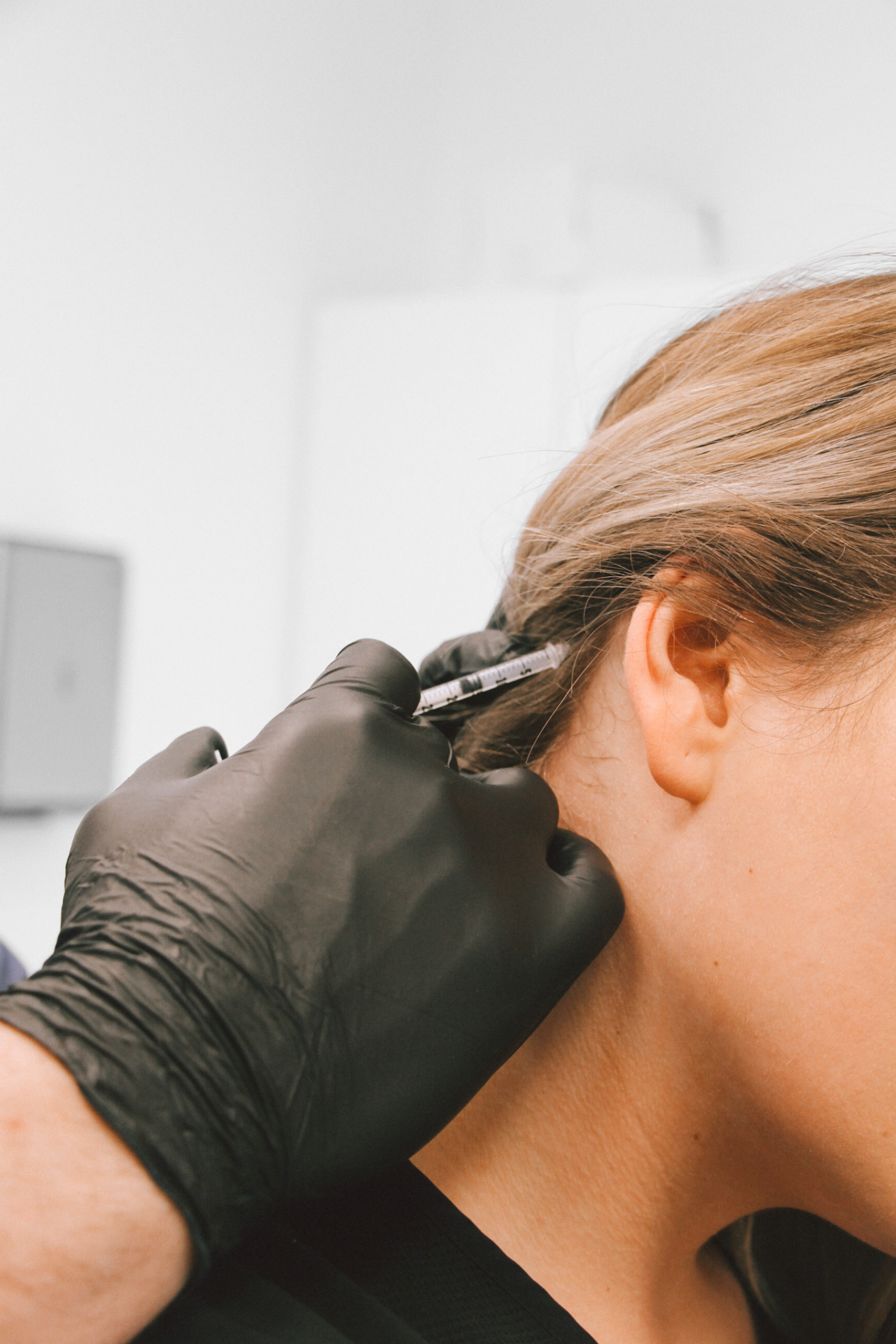 Botox being injected behind patient's ear