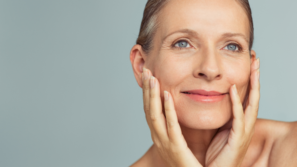 An image of a confident woman smiling gently towards the camera, set against a calm, neutral background. She has radiant, clear skin and a relaxed expression, embodying vitality and health. This photo is associated with a blog that focuses on skin health.